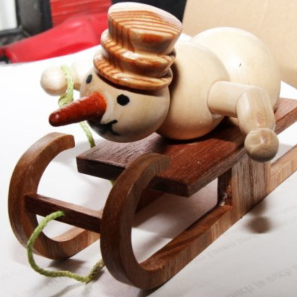 Schneemann liegend auf Schlitten aus Holz gedrechselt